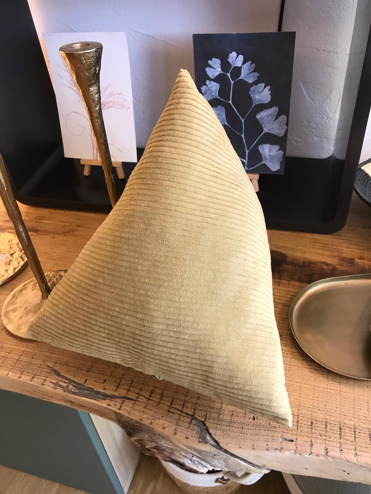 Coussin triangulaire en velours côtelé beige posé sur une étagère en bois