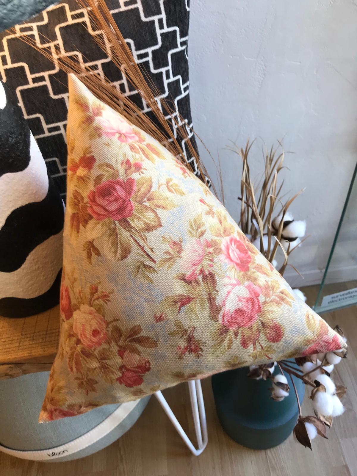 Coussin triangulaire à motif floral rose et ocre dans une composition décorative