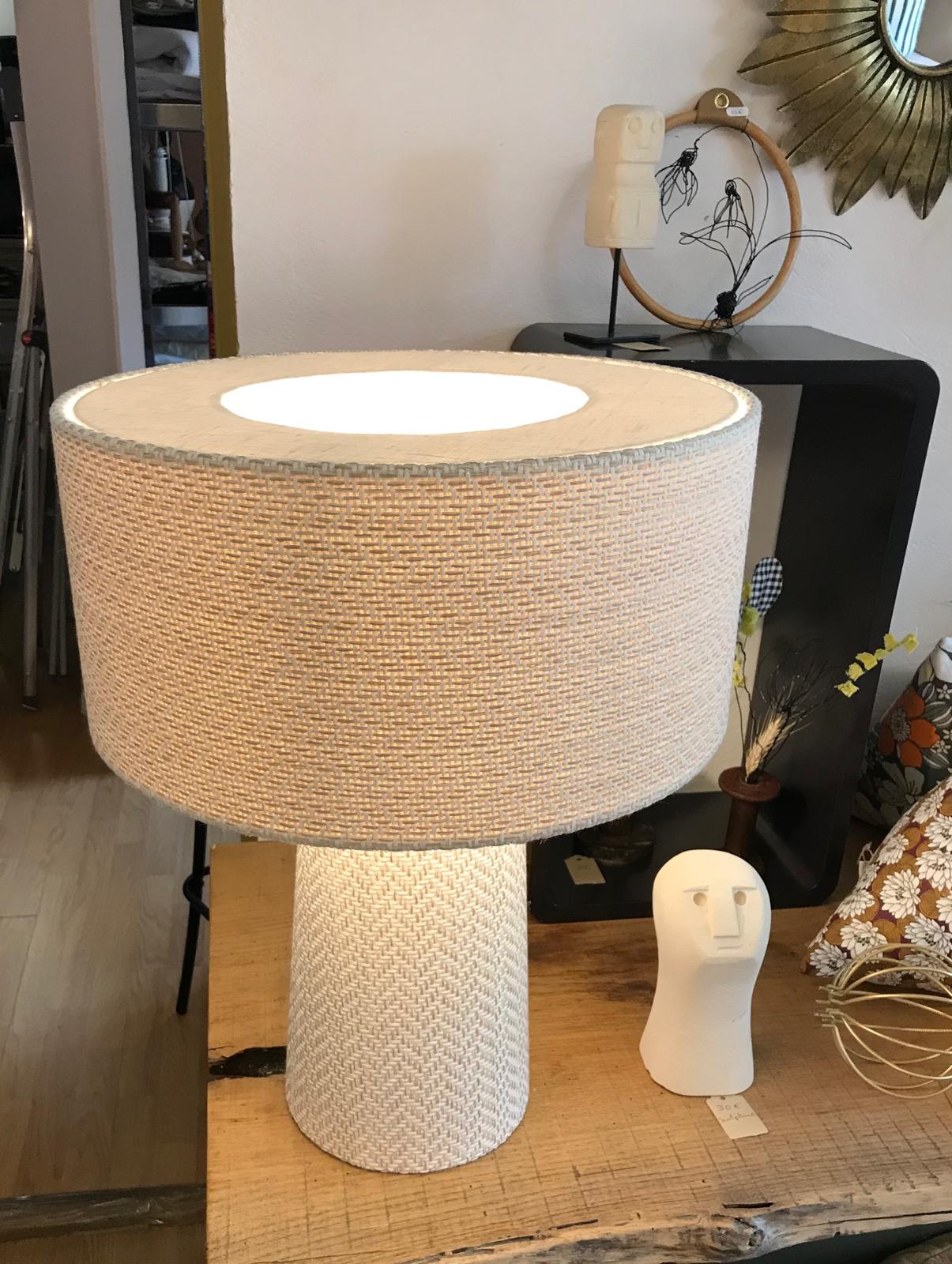 Lampe basse ronde en matiÃ¨re tressÃ©e claire posÃ©e sur une table en bois