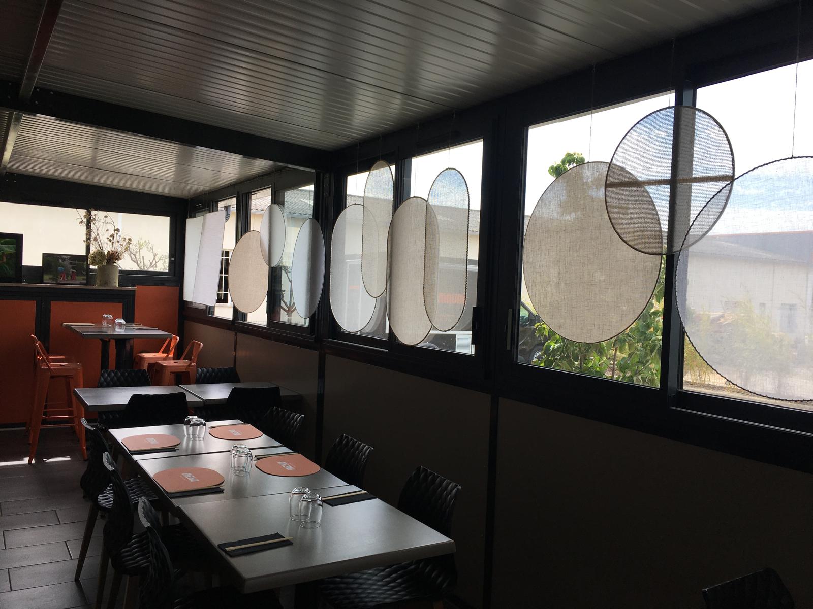 Vue d'ensemble d'une installation de panneaux textiles suspendus dans une pièce lumineuse