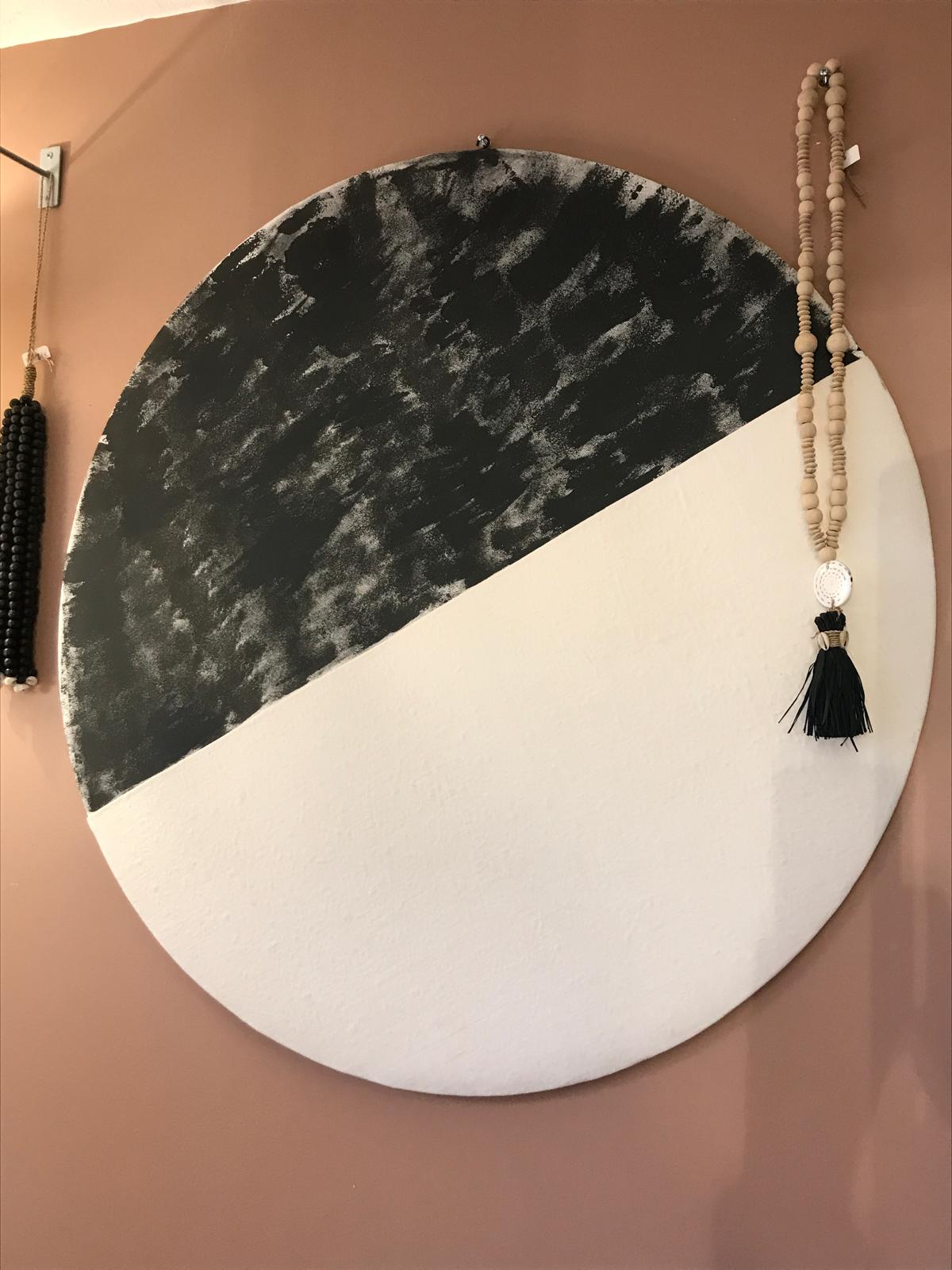 Grand tableau rond en tissu blanc et noir accroché sur un mur terracotta