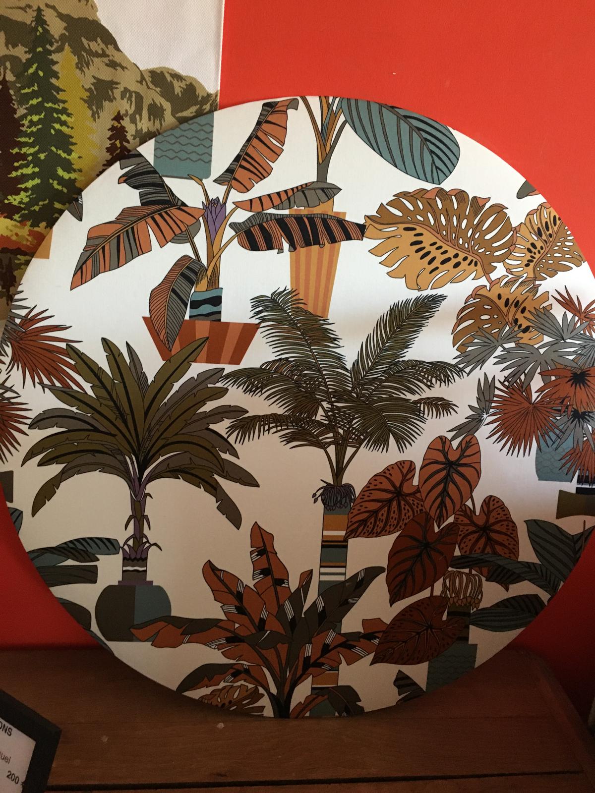 Tableau rond en tissu imprimé tropical posé sur un meuble en bois