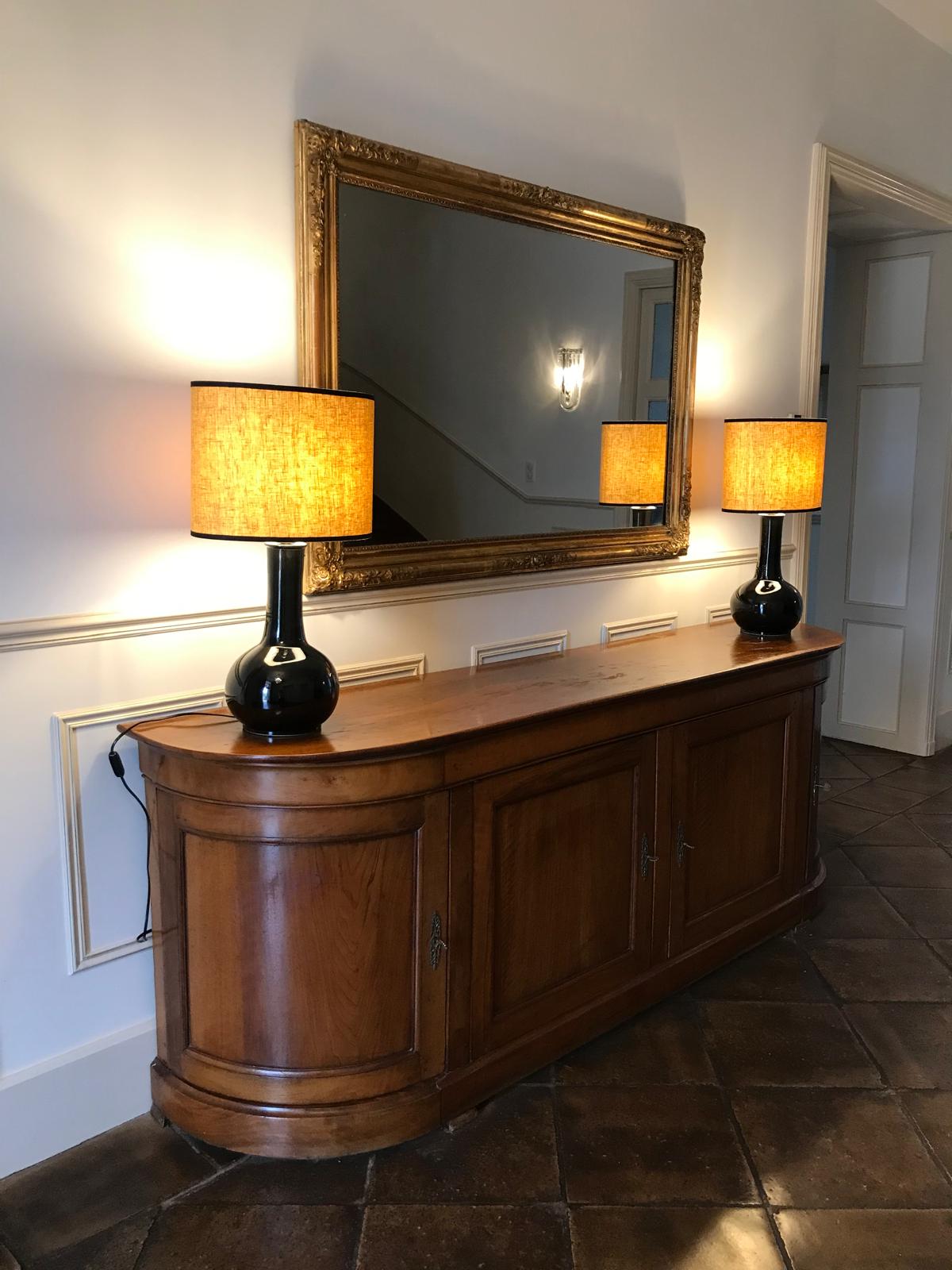 Deux lampes noires avec abat-jour chauds sur un meuble en bois et grand miroir
