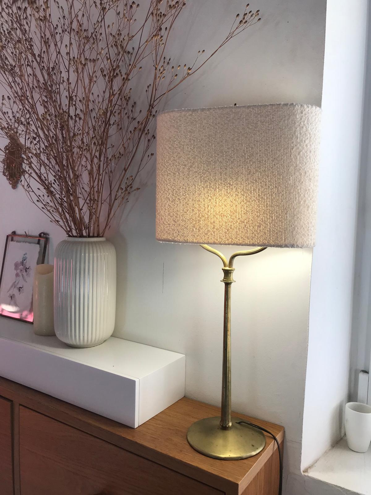 Lampe en laiton avec abat-jour carré texturé beige près d'un vase blanc