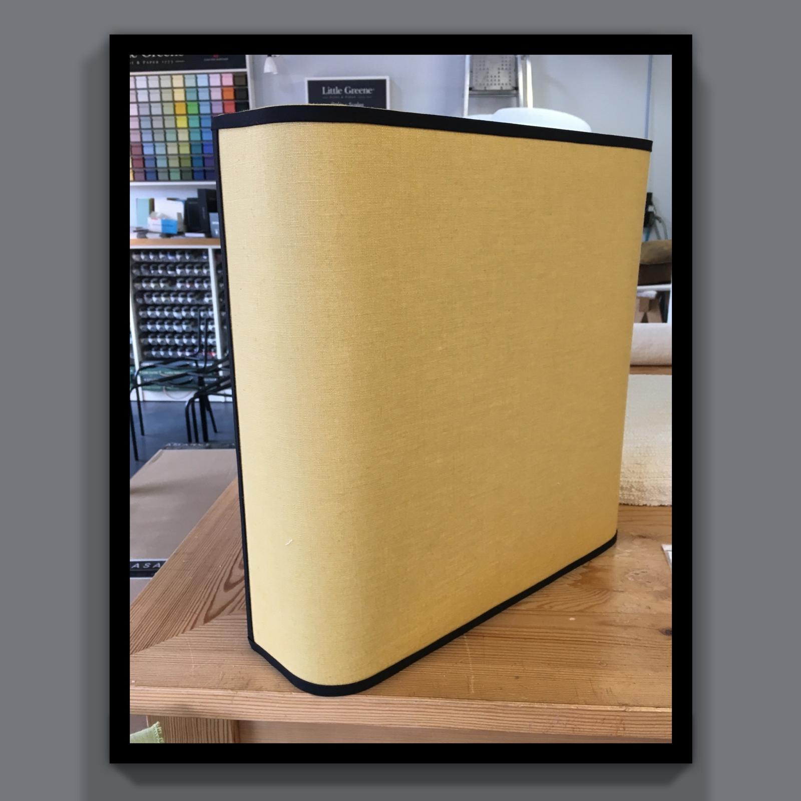 Applique courbe jaune bordée de noir posée sur une table d'atelier