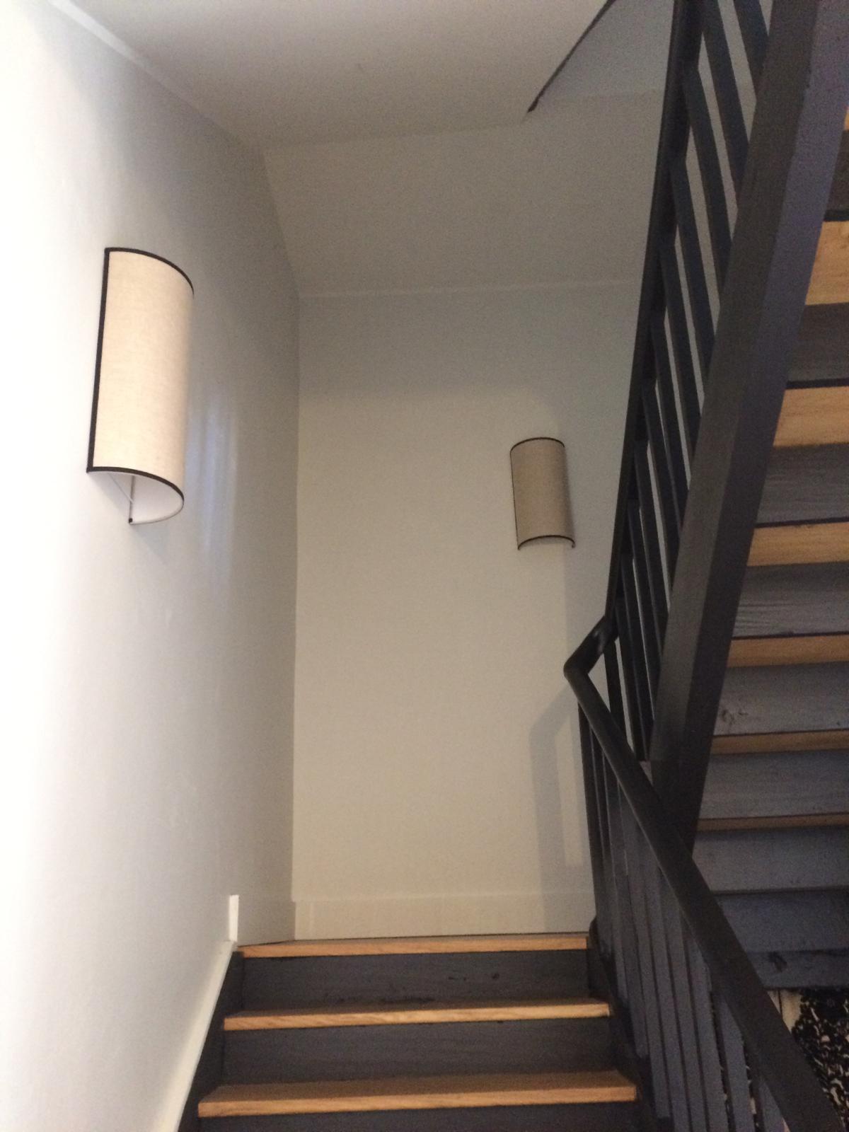 Deux appliques hautes et claires installées dans une cage d'escalier