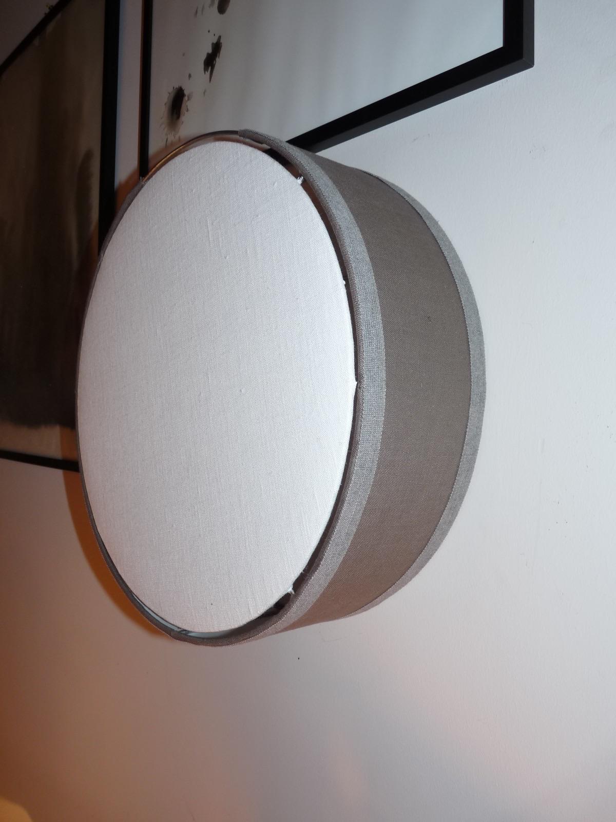 Applique ronde en tissu taupe vue en détail sur un mur