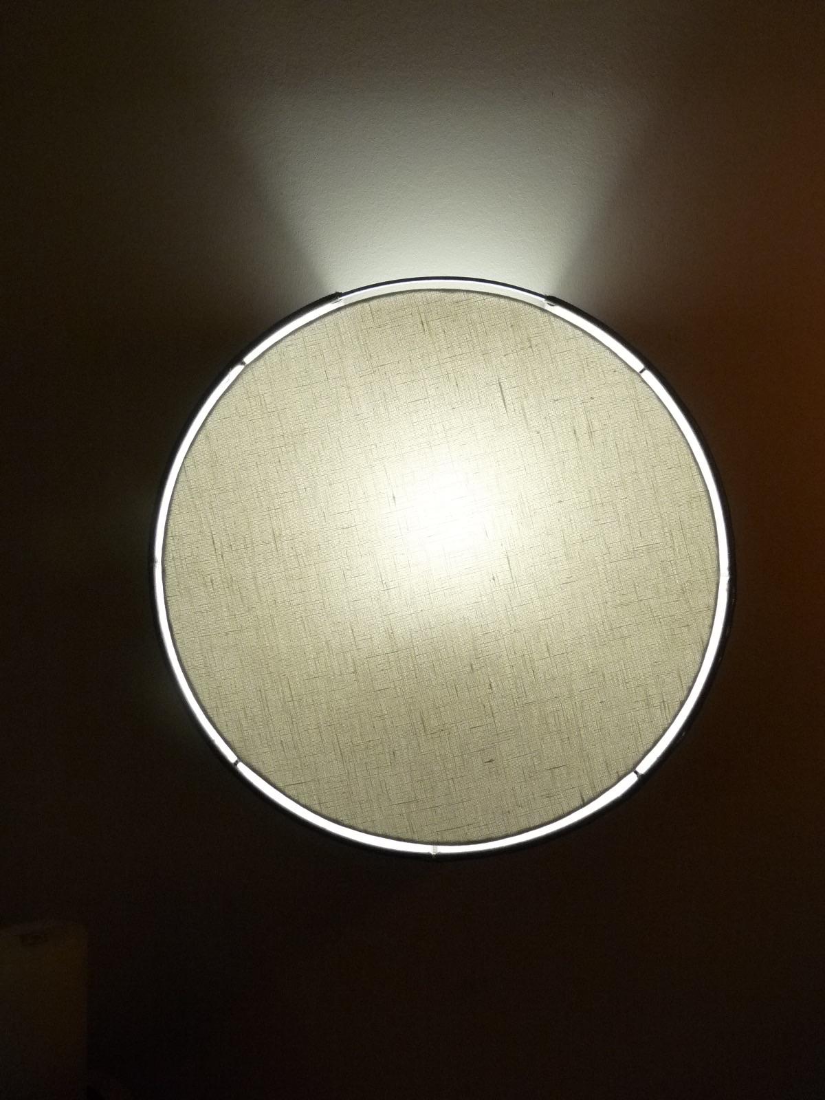 Applique ronde rétroéclairée diffusant un halo circulaire sur le mur