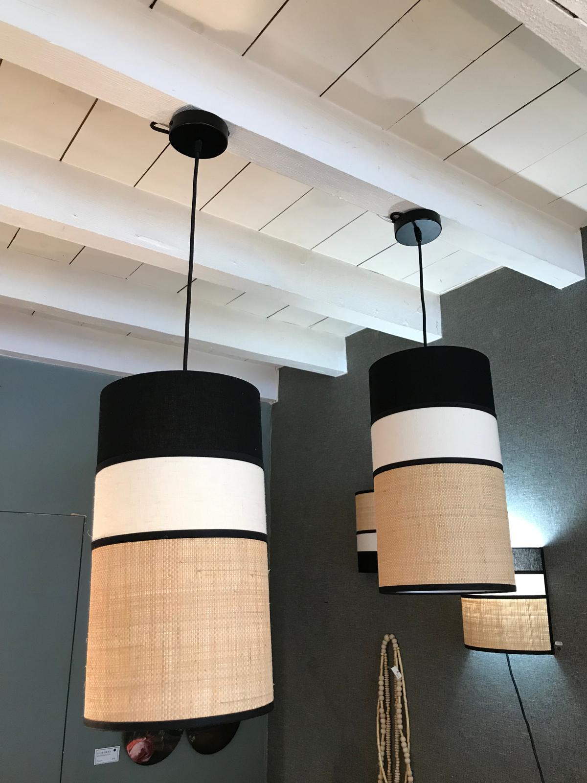 Suspensions cylindriques en noir, blanc et fibre naturelle dans un espace à poutres